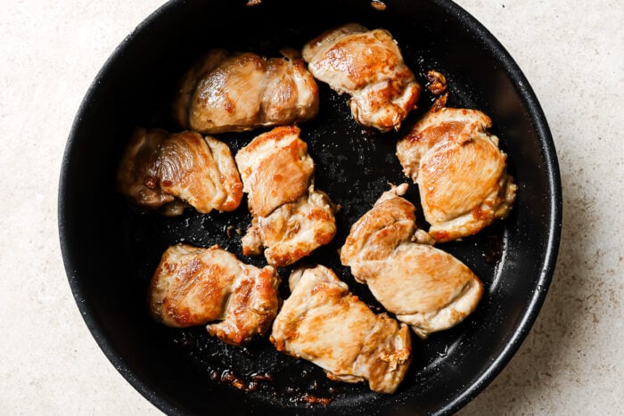 Raw chicken thighs in a cast iron skillet, ready to cook for an easy honey garlic chicken recipe.