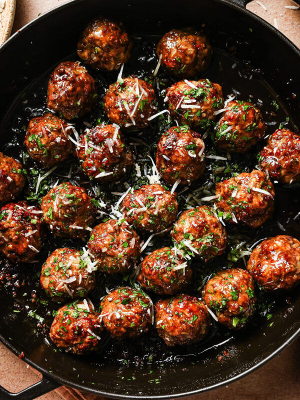 A pan filled with Honey Garlic Meatballs, glazed to perfection and garnished with chopped herbs and grated cheese.