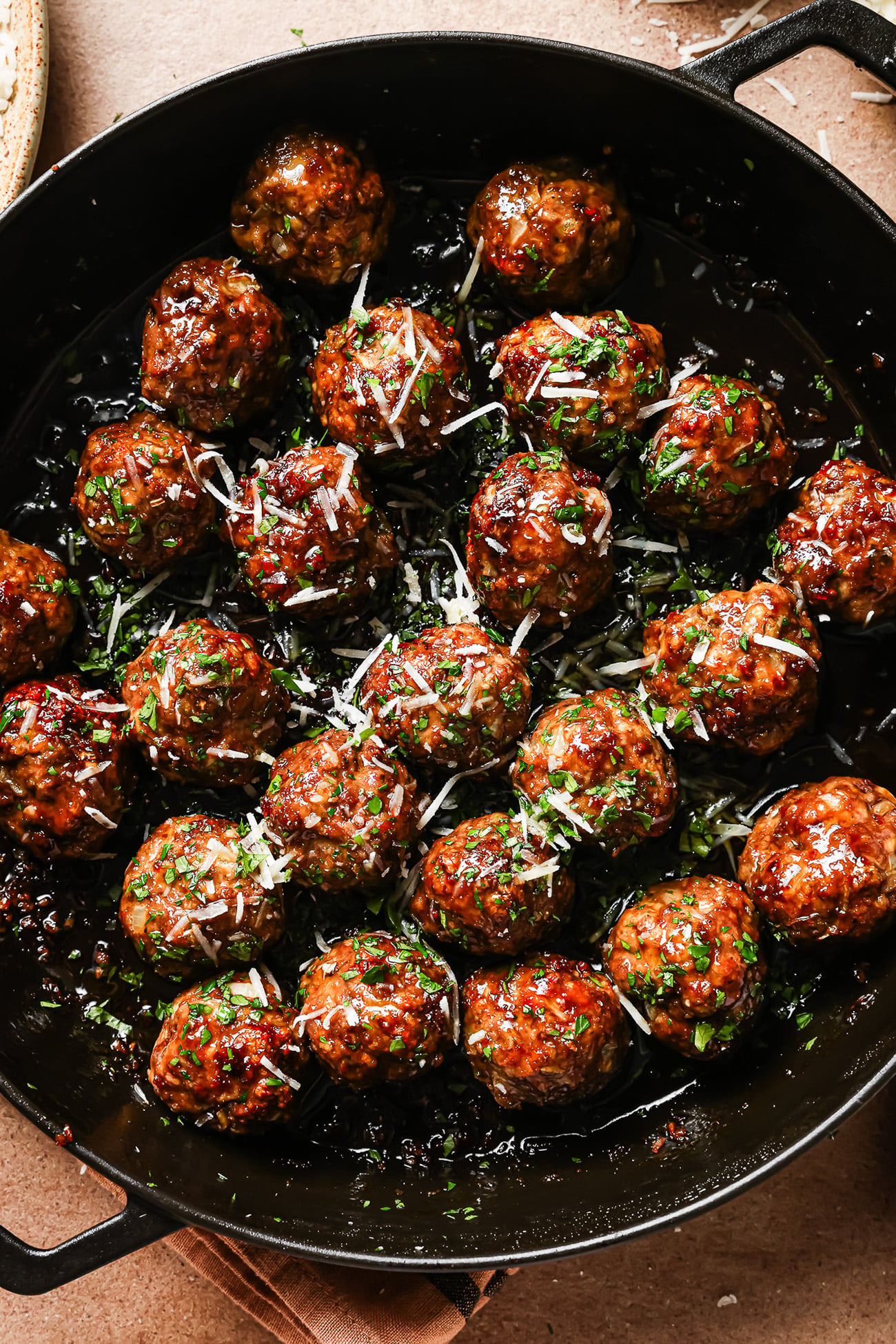 A pan filled with Honey Garlic Meatballs, glazed to perfection and garnished with chopped herbs and grated cheese.