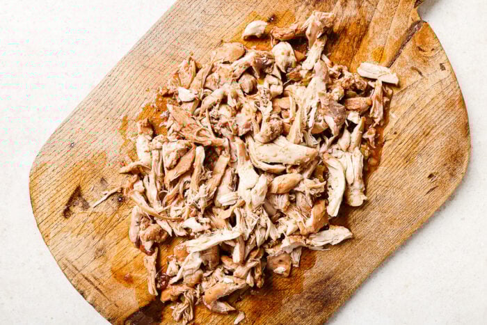 Tender shredded chicken on a wooden cutting board.