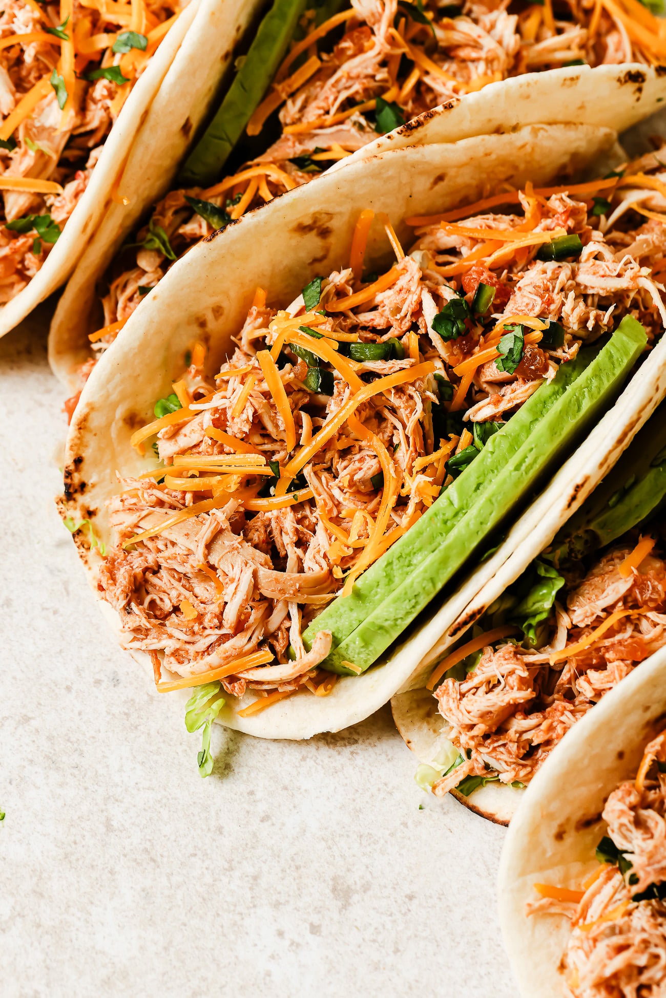 Close-up view of slow cooker chicken tacos filled with shredded chicken, salsa, and fresh toppings.