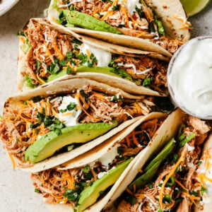 Slow Cooker Chicken Tacos with fresh toppings on a kitchen countertop.