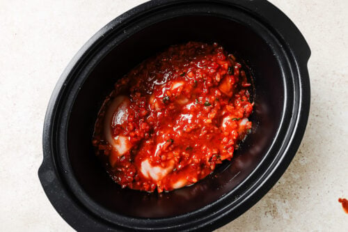 Chicken breasts with salsa inside a slow cooker.