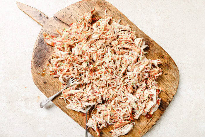 Tender shredded chicken on a wooden cutting board.