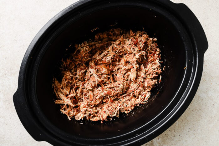 Tender shredded chicken mixed with salsa in a slow cooker.