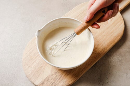 horseradish sauce in a white bowl on a wooden board.