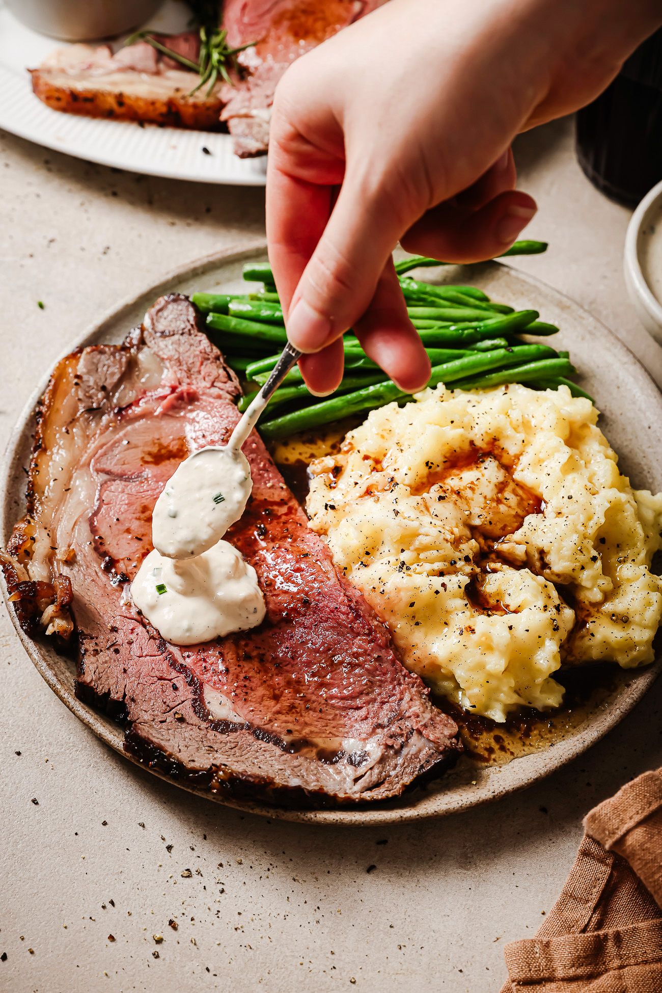 Prime rib plated with mashed potatoes, green beans, and creamy horseradish sauce — a perfect holiday dinner.