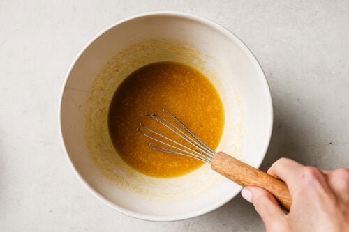 Rich pecan pie brownie batter in a white mixing bowl, ready to be poured into the pan for baking.