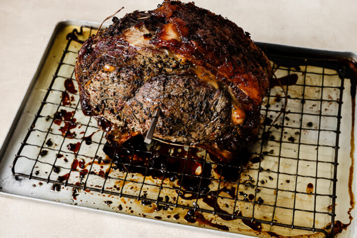 Roasted prime rib resting on a baking sheet after coming out of the oven, ready to slice for the reverse sear prime rib recipe.
