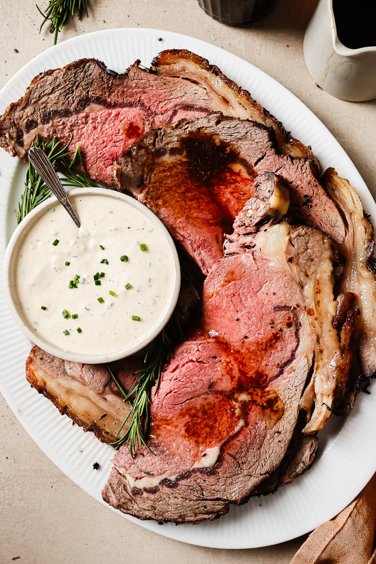 Juicy slices of reverse sear prime rib served with horseradish sauce on a plate, showing the juicy and perfectly cooked interior.