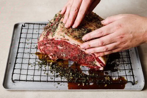 Raw prime rib roast on a wire rack, marinated with Worcestershire sauce and herbs, ready for the reverse sear method