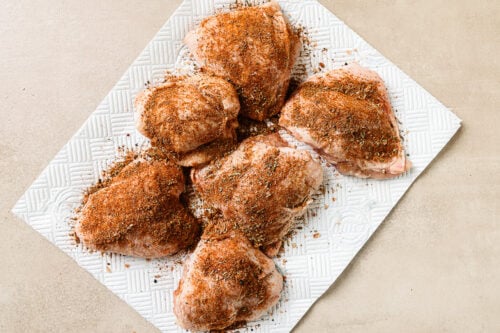 seasoned raw chicken thighs on a countertop.