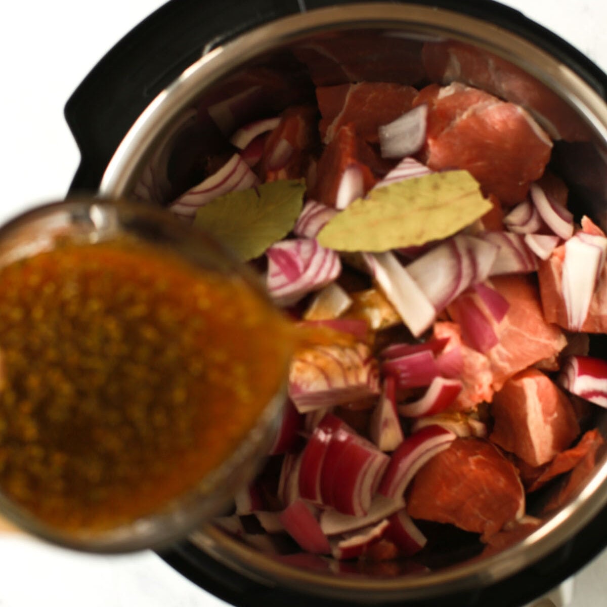 overhead view of beef broth being poured inside of an instant pot