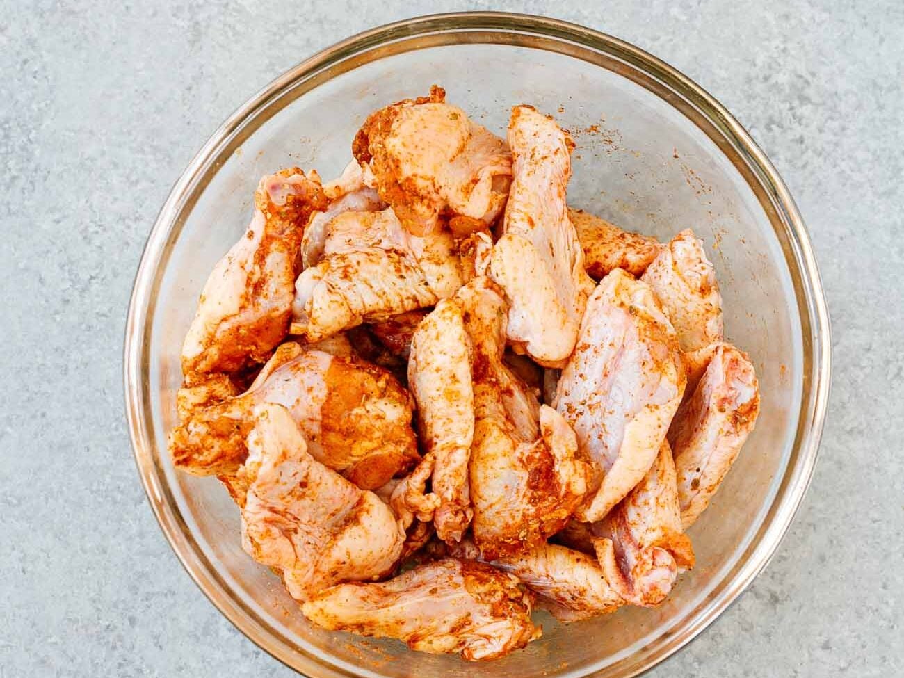 seasoned chicken wings in a glass bowl