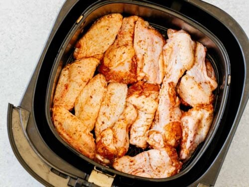 overhead view of an air fryer basket containing raw chicken wings