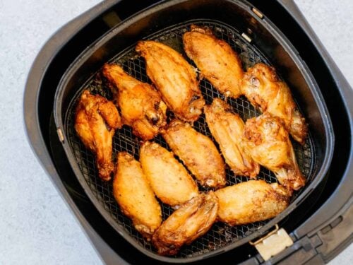 overhead view of an air fryer basket containing cooked chicken wings