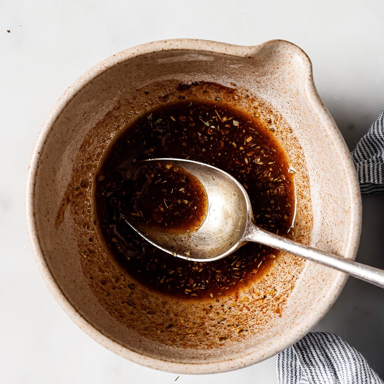 An overhead view of seasonings and olive oil in a mixing bowl.