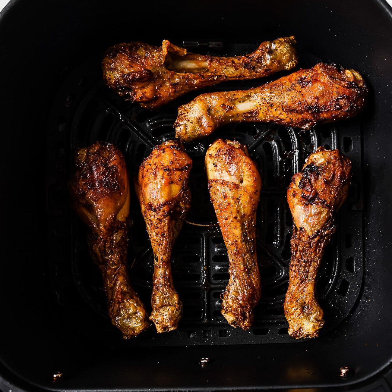 Cooked chicken legs in an air fryer basket.