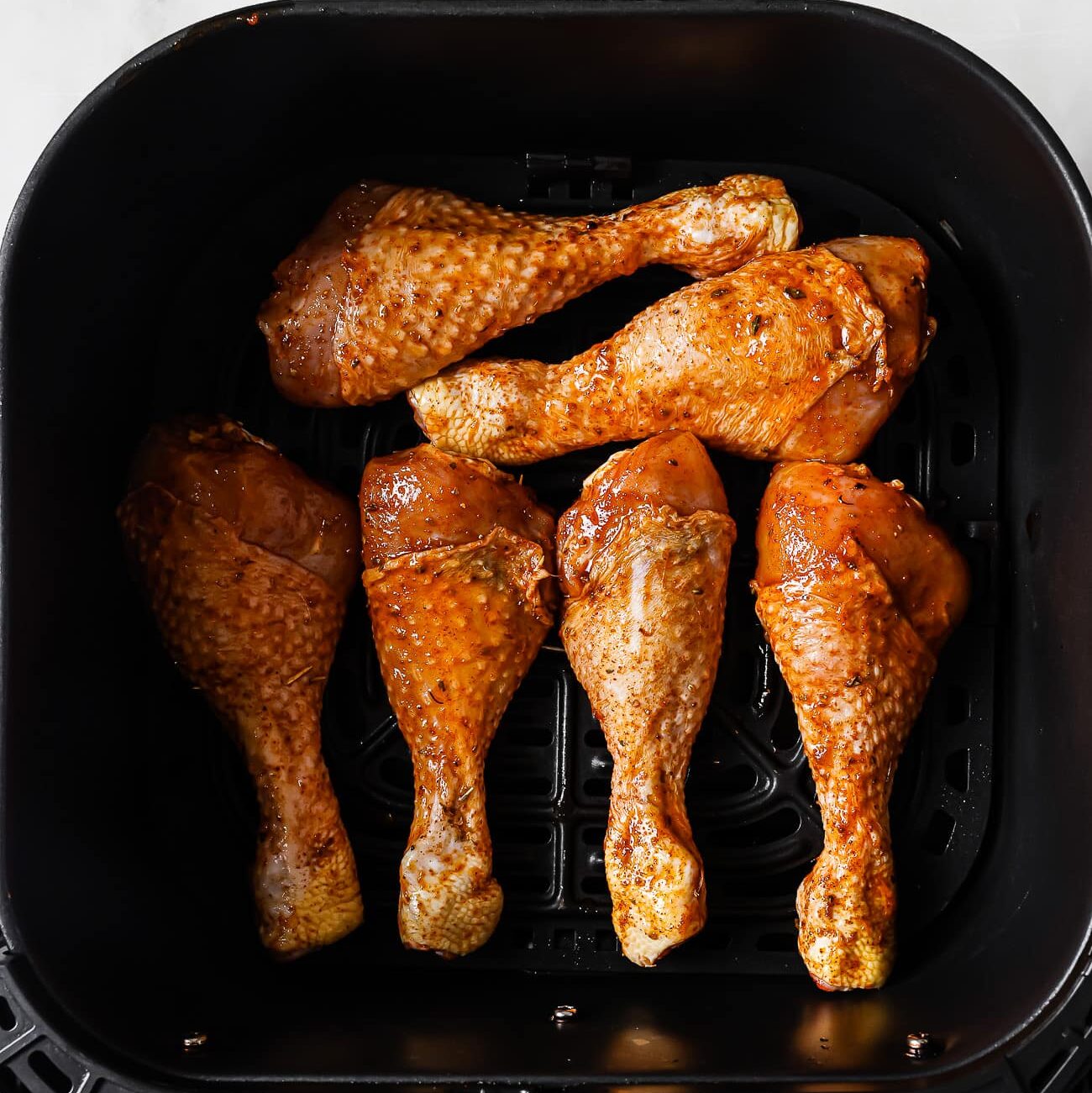 Chicken legs arranged in an air fryer basket.