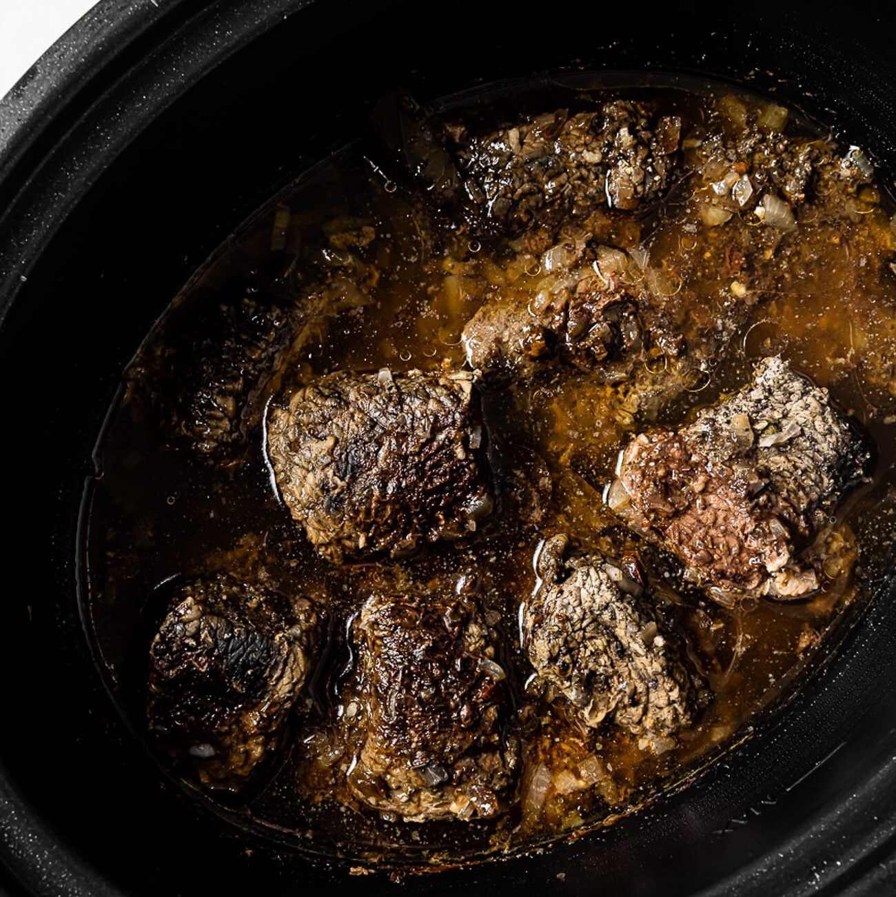 An overhead view of cooked beef in a slow cooker.