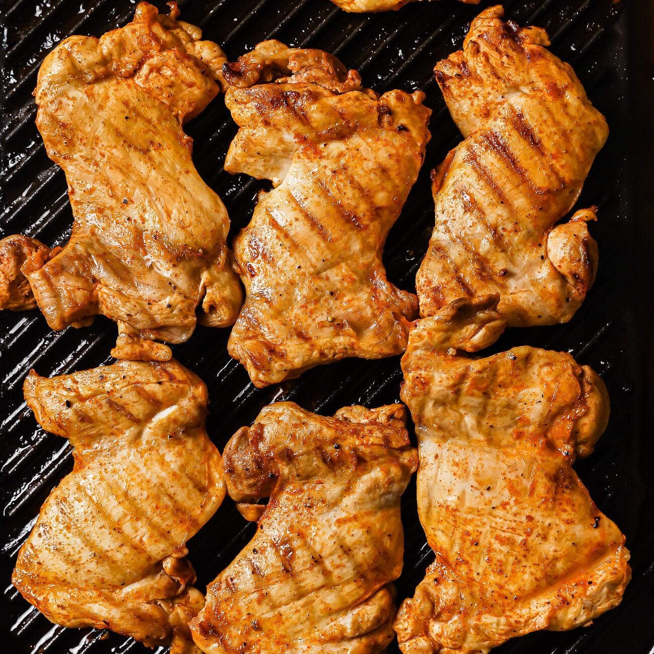 Chicken thighs cooking on a grill pan.