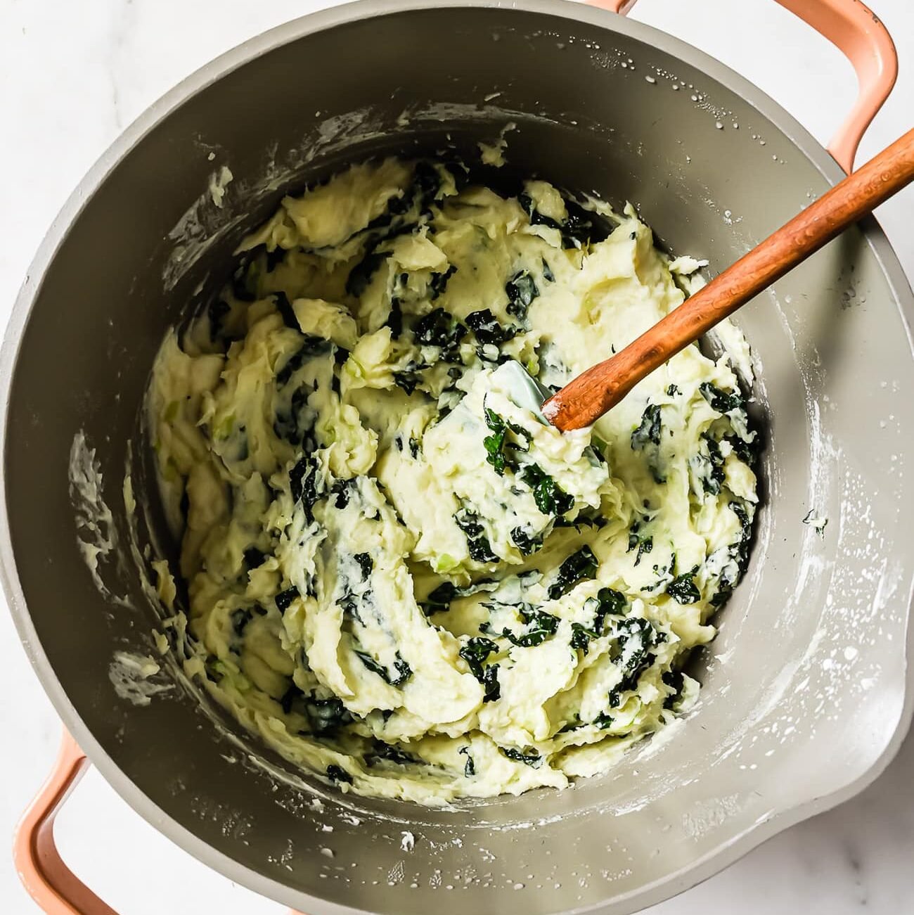 Colcannon in a large pot with a wooden-handled spatula in it.