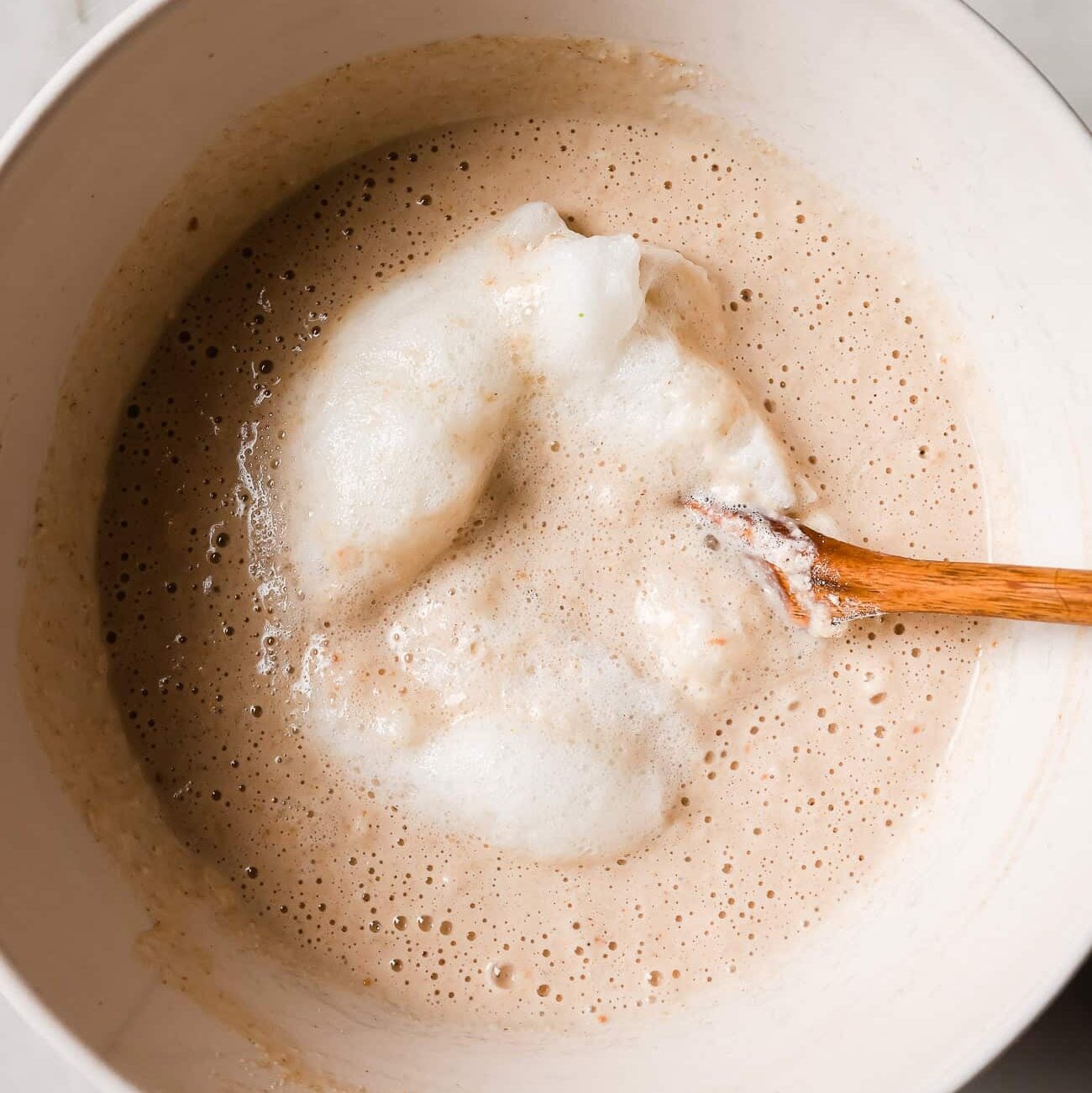 Wet ingredients and beaten egg whites inside a white bowl.