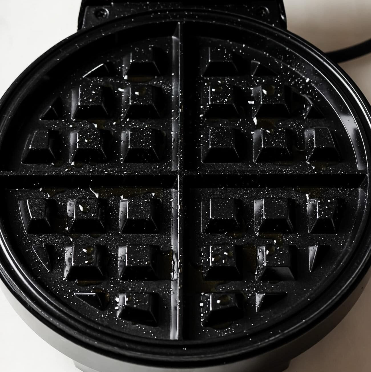 waffle iron open with cooking oil.