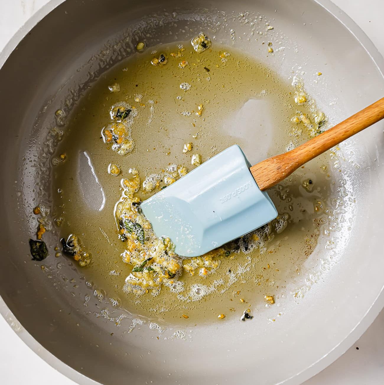 An overhead view of butter, garlic, and sage in a skillet.