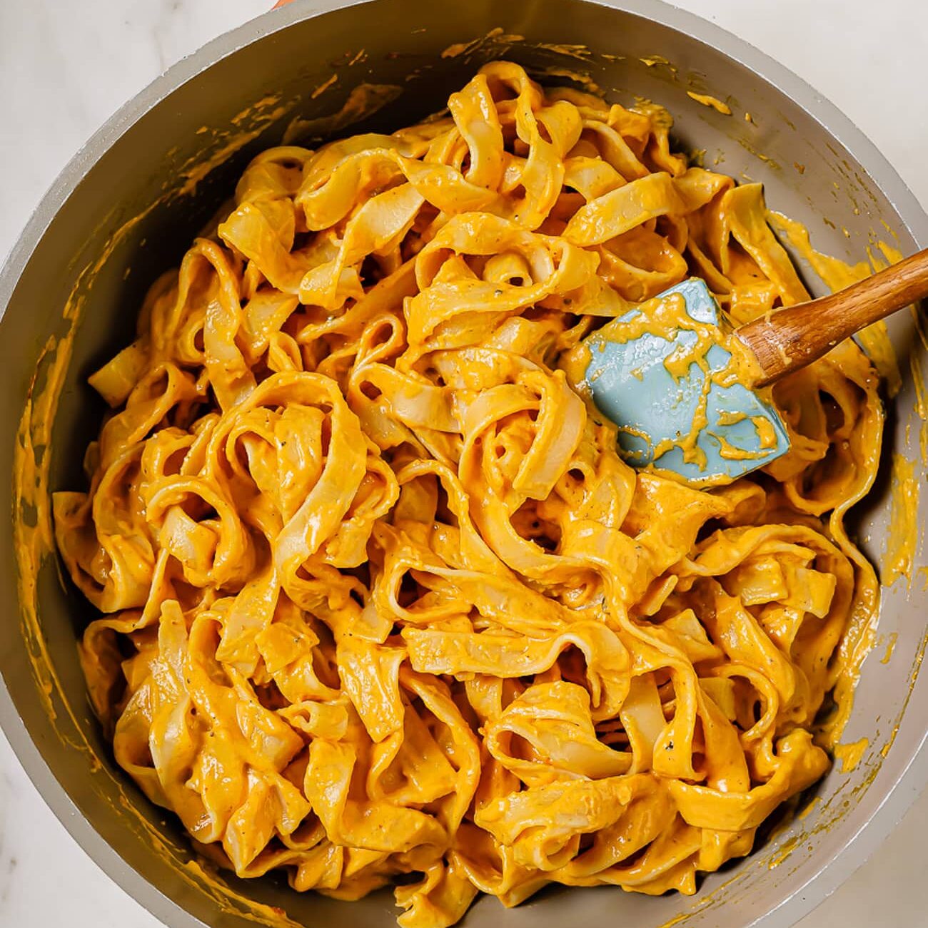 Cooked fettuccini noodles added to the sauce.