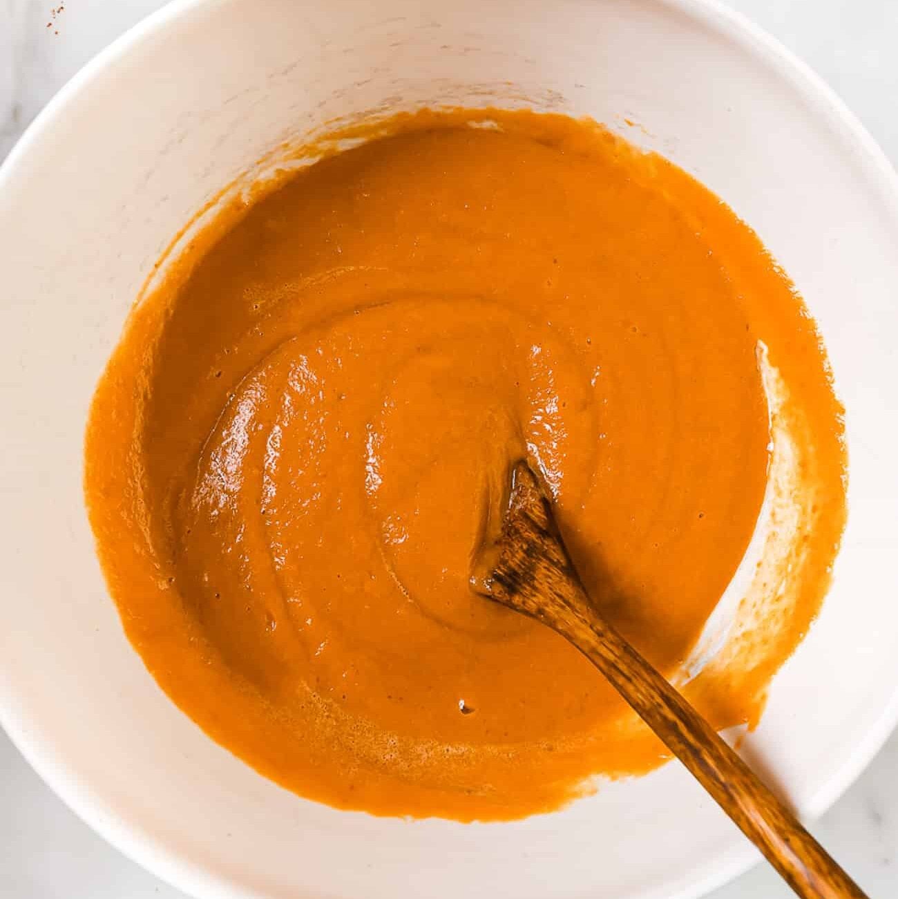 The pumpkin, oil, and milk added to the bowl.