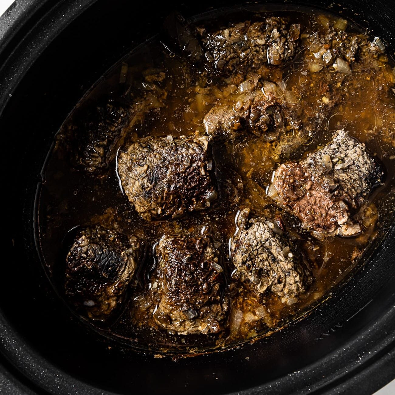 Pieces of cooked beef in the slow cooker.