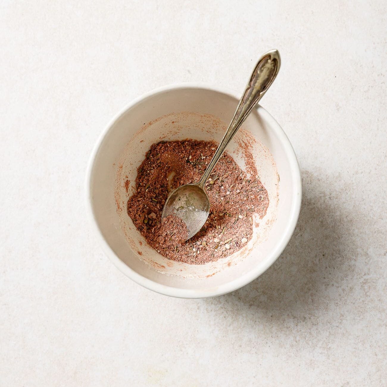A small bowl of pre-mixed spices with a spoon in it.