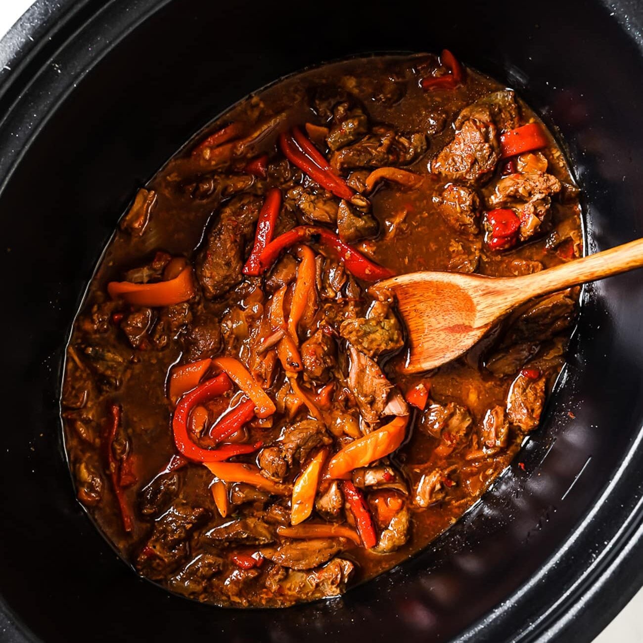 An overhead view of pepper steak in a slow cooker.