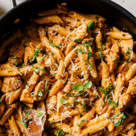 A skillet filled with creamy penne pasta, shredded chicken, herbs, and grated cheese, with a wooden spoon resting inside. The Marry Me Chicken Pasta text appears at the top, perfectly capturing the irresistible dish that promises comfort in every bite.